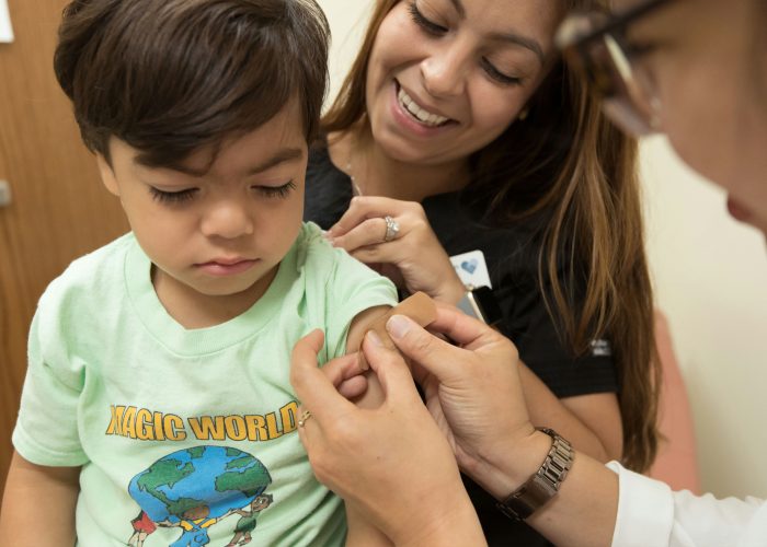 boy receiving bandaid from doctor after vaccine